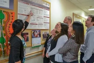 A group from the Datta lab staring at a scientific poster posted on a hallway bulletin board 