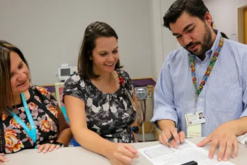 Three physicians review printed pages together
