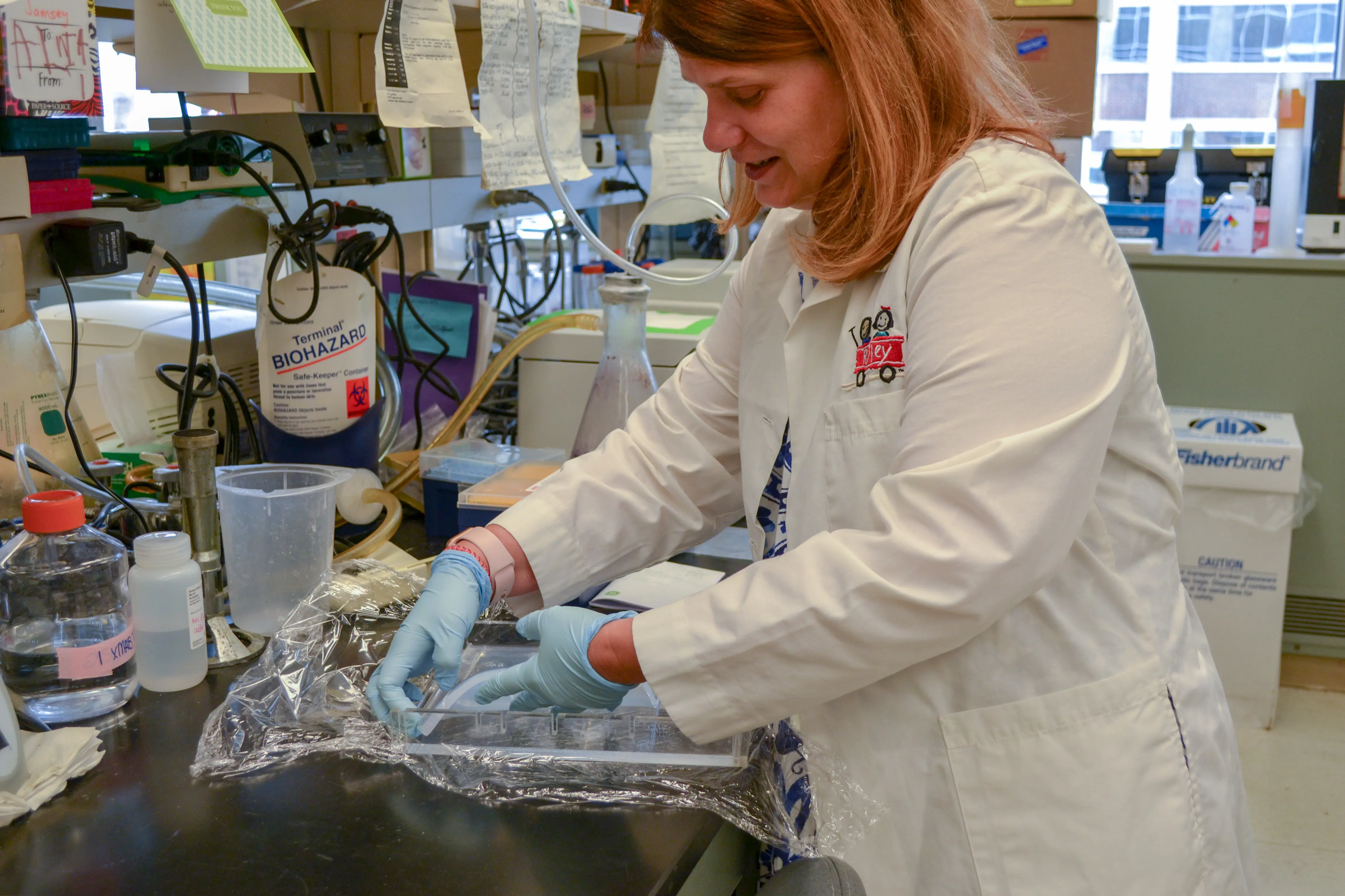 A woman in a lab coat prepares a sample in the research lab