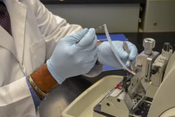 Close up shot of gloved hands running an experiment with a research instrument.