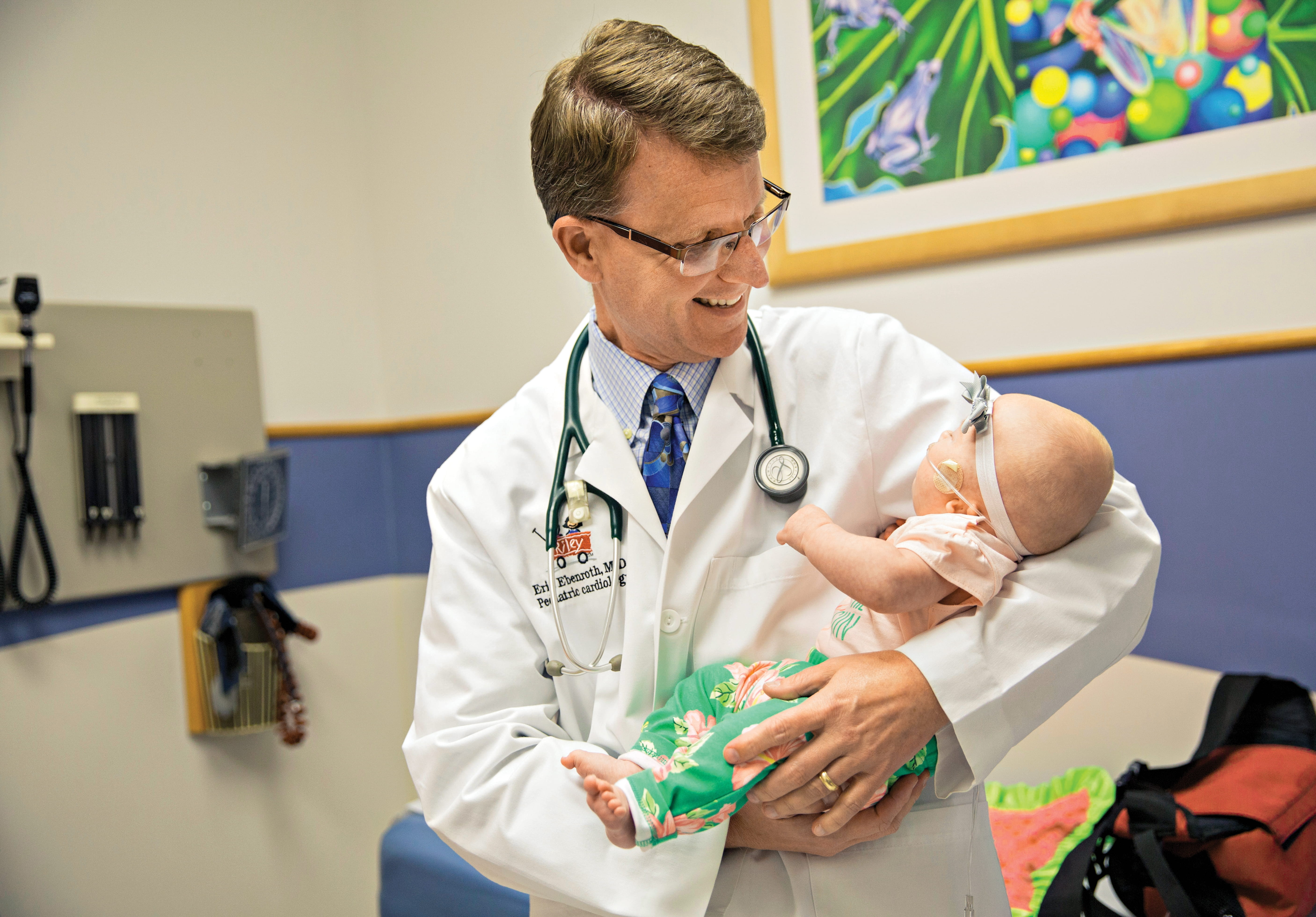 Eric Ebenroth, MD, holds a baby in pediatric cardiology clinic