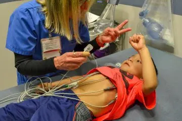 Faculty member helps a patient get ready for an electrophysiology study.