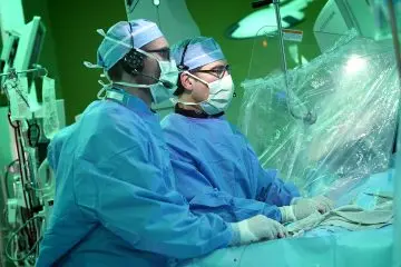 Two faculty dressed in surgical gear performing surgery. 