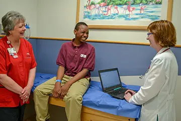 Provider working on a computer with a patient and nurse