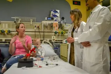 A care team, patient and family member in a hospital bed