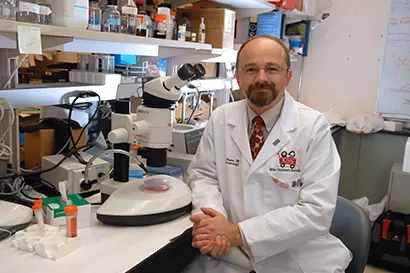 Scientist sitting next to a microscope