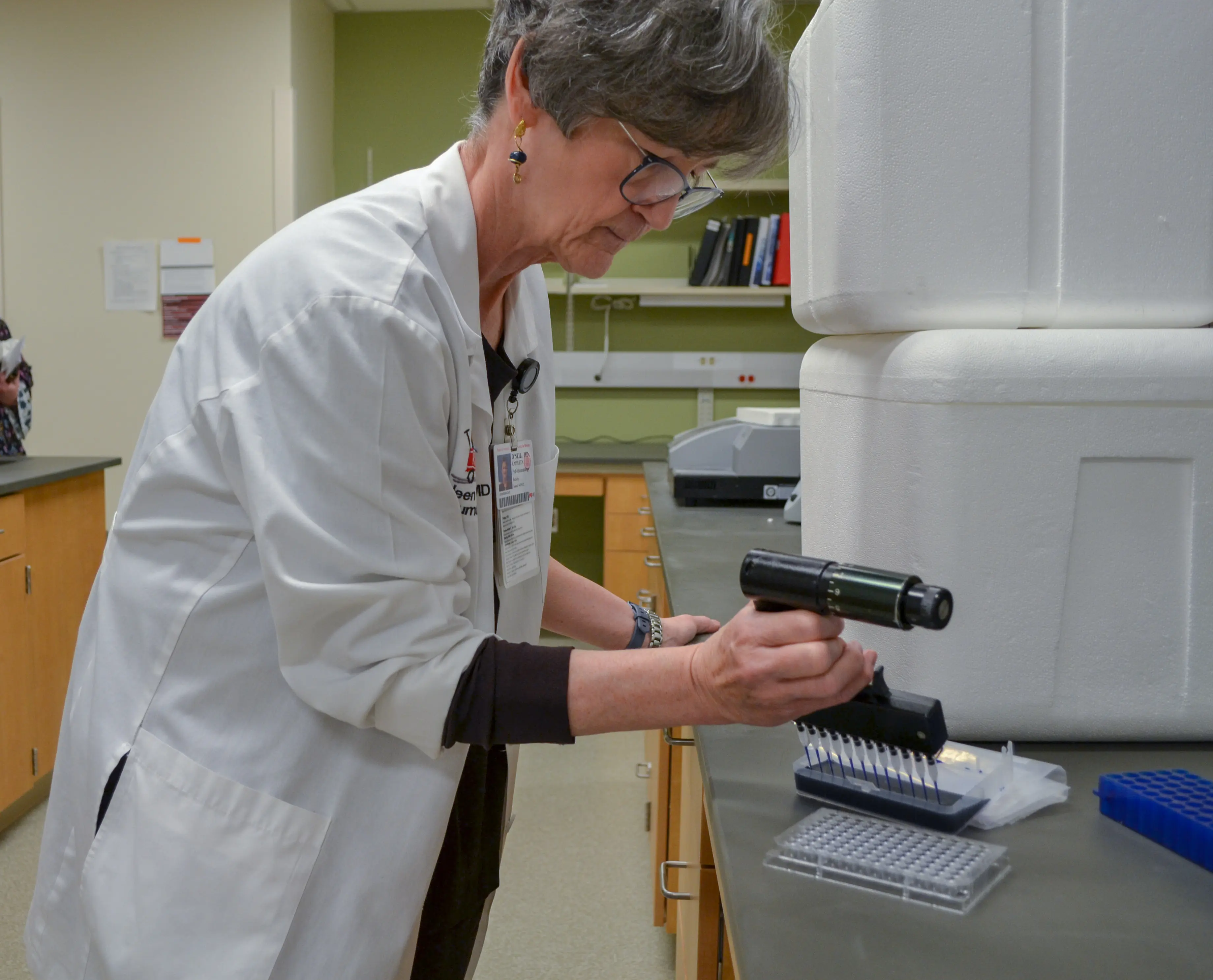 A woman in a lab coat prepares a sample in the research lab