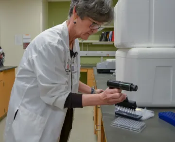 A woman in a lab coat prepares a sample in the research lab
