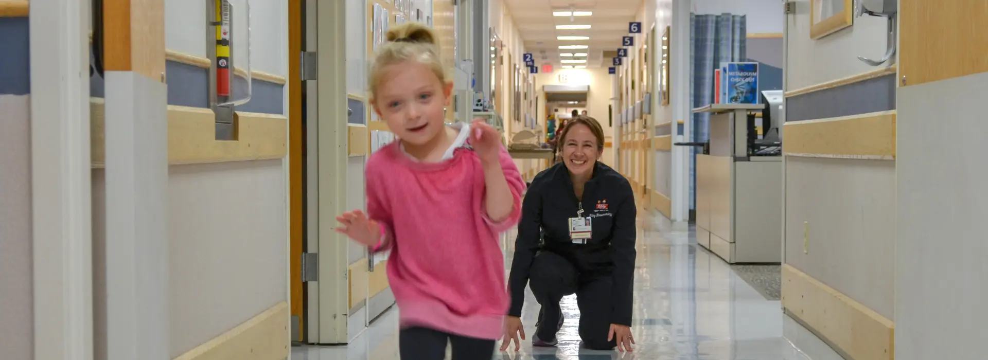 A provider and a child walking down the hallway