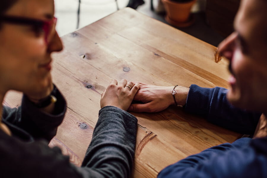 two people talk and look at each other while touching hands