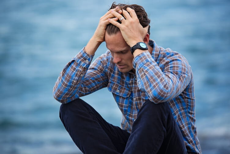 a man sits in frustration with his hands on his head