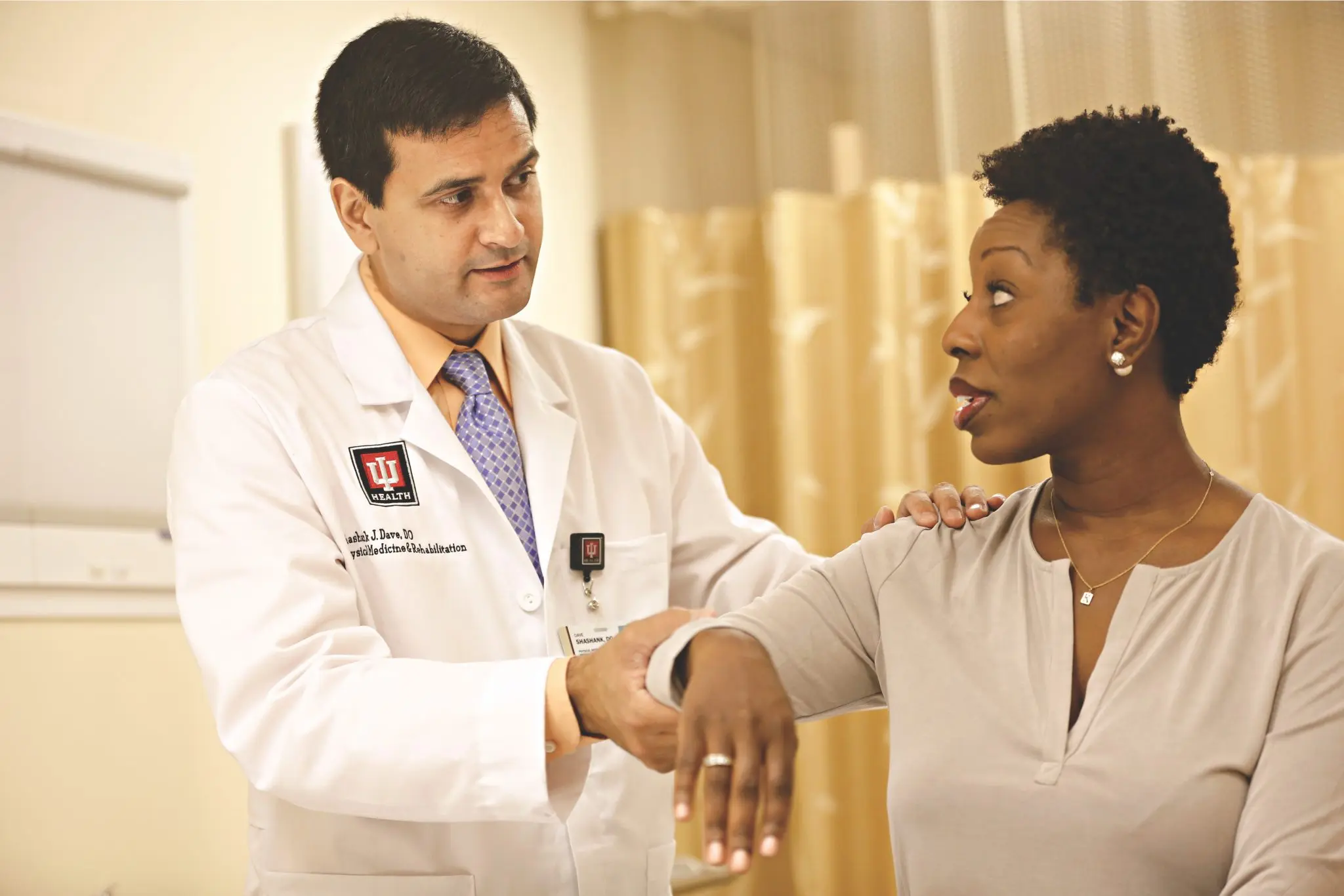 Shashank Dave examines a patient's arm and shoulder