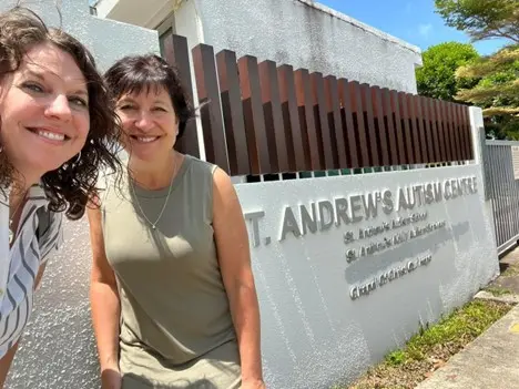 two women pose in front of the St. Andrews Autism Research Centre sign