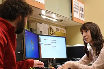 Two medical physicists discuss treatment plans together in a clinic work space