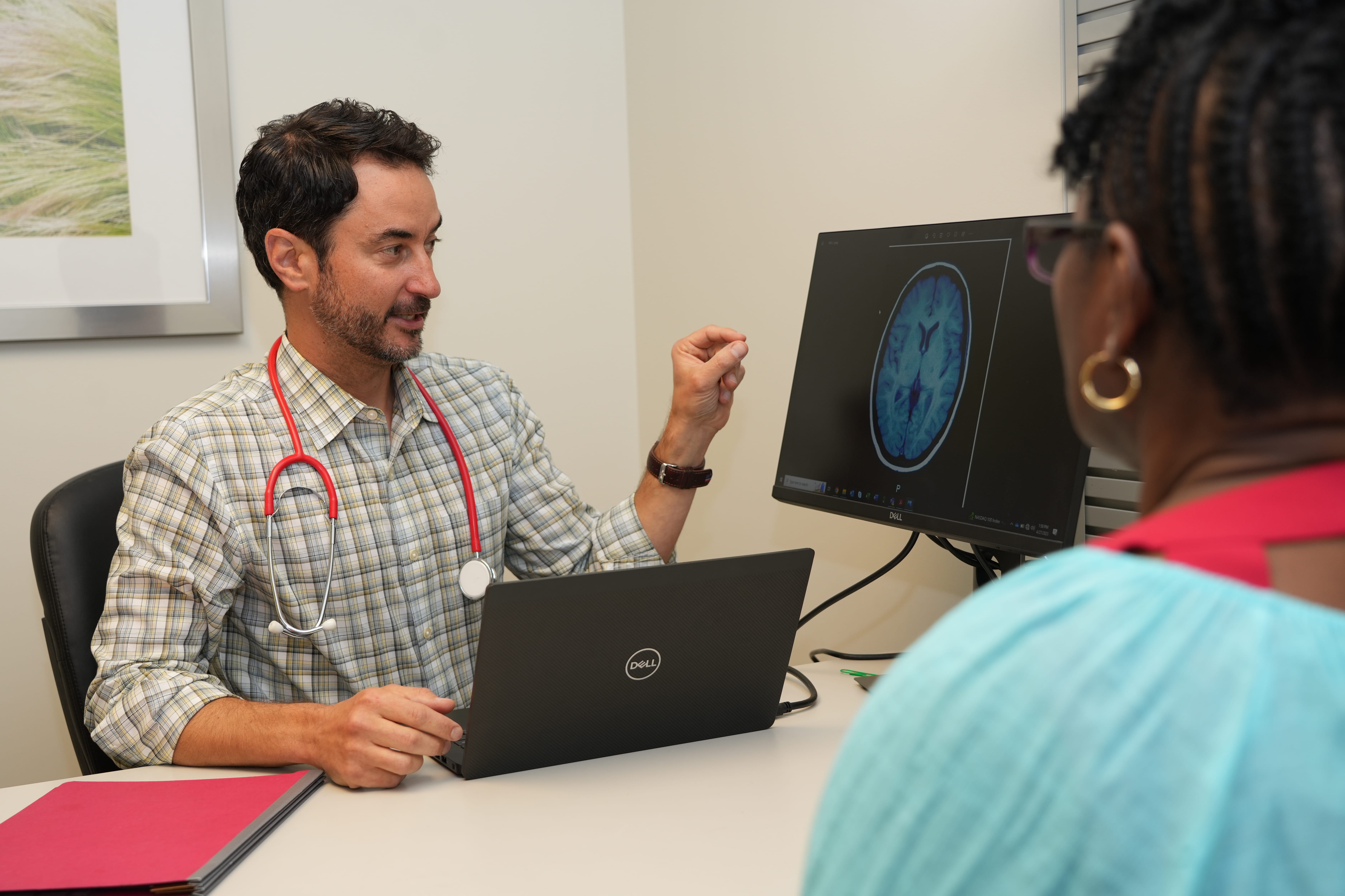 A male physician explains the results of a neuro scan to a female patient.