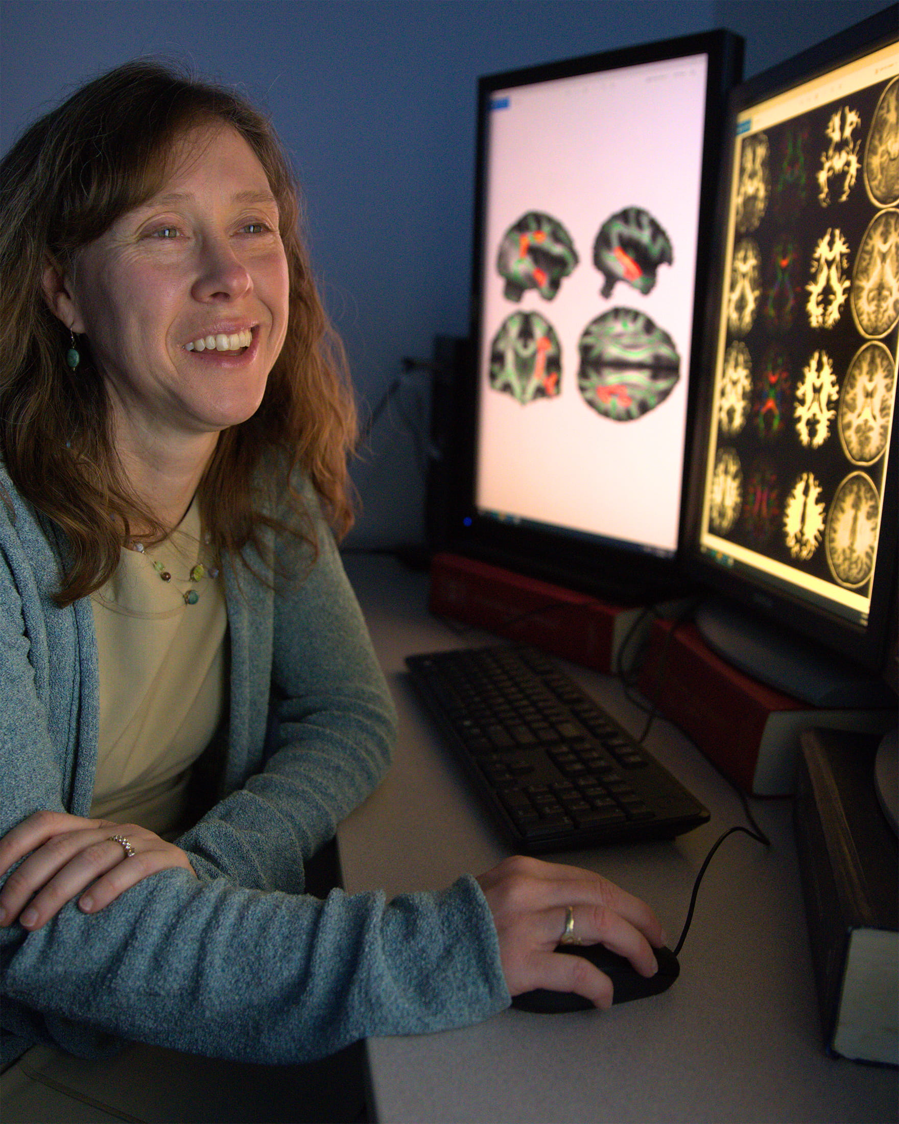 female radiologist smiling while looking at neuro scans on a monitor