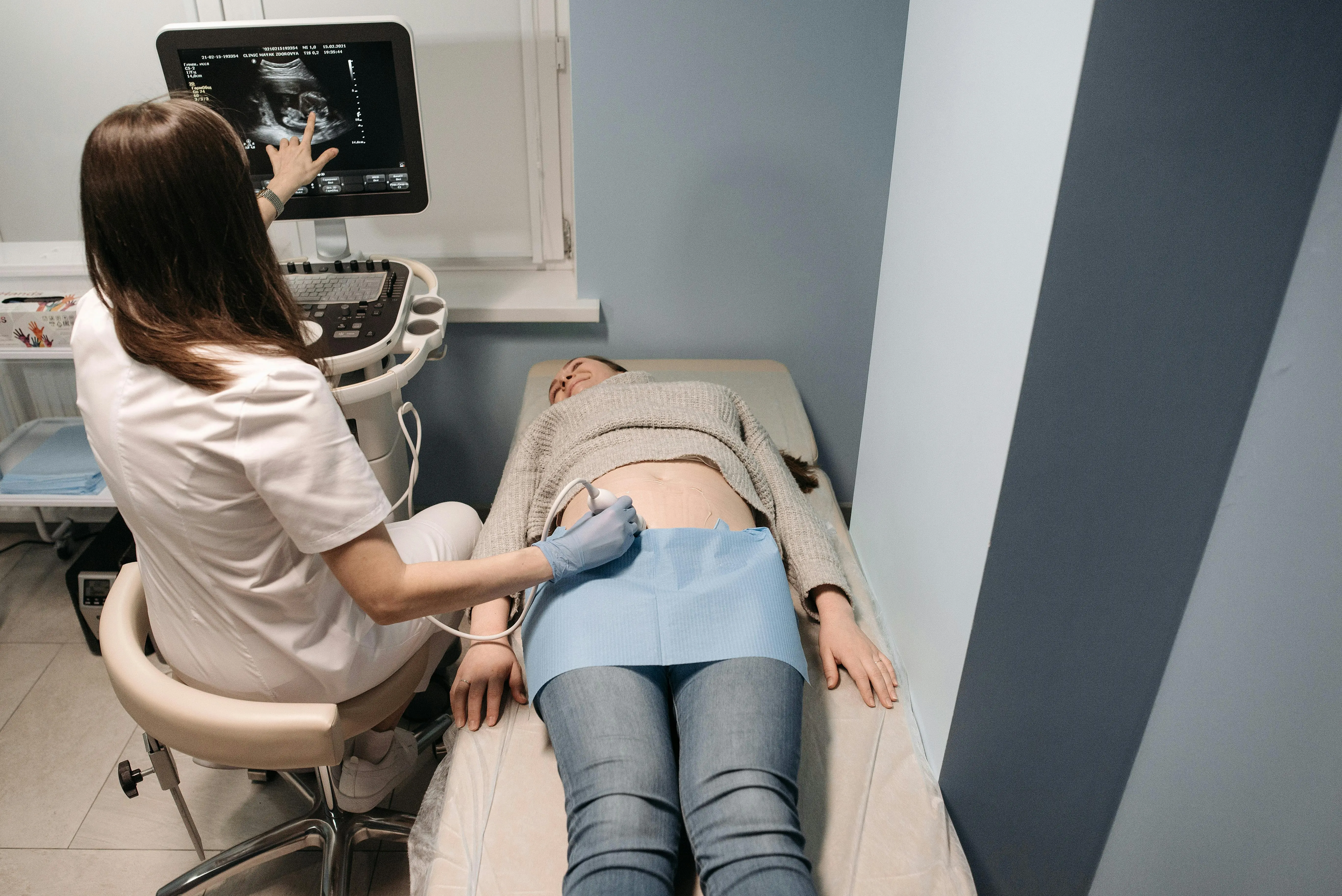 A female student practices an ultrasound while a female faculty member observes.