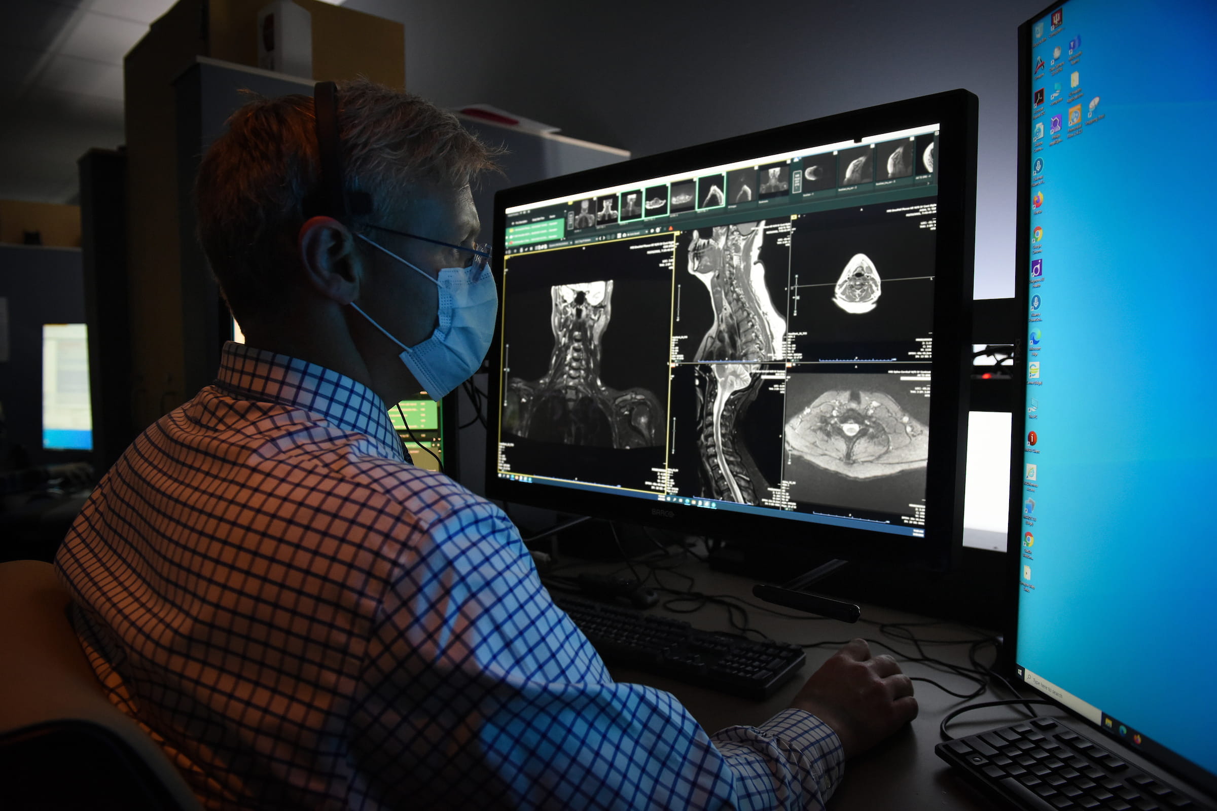 A male radiologist studies images of the head/neck.