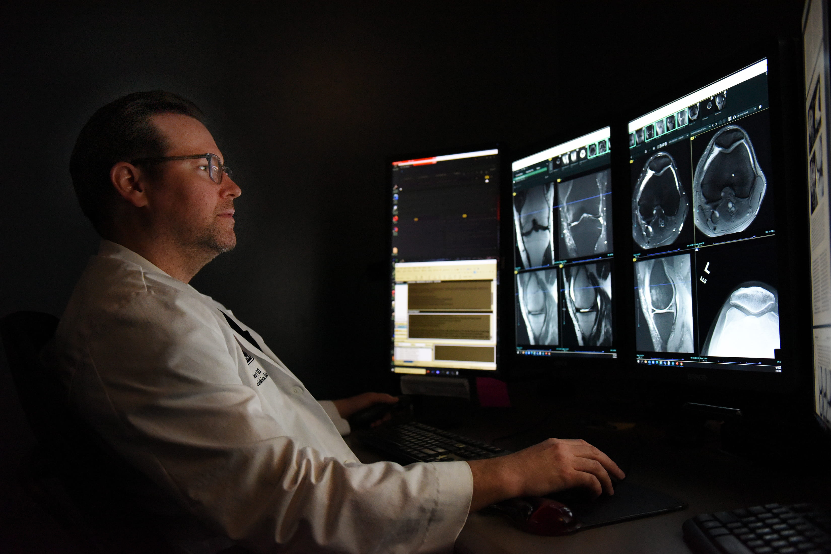 A male physician studies a knee scan.