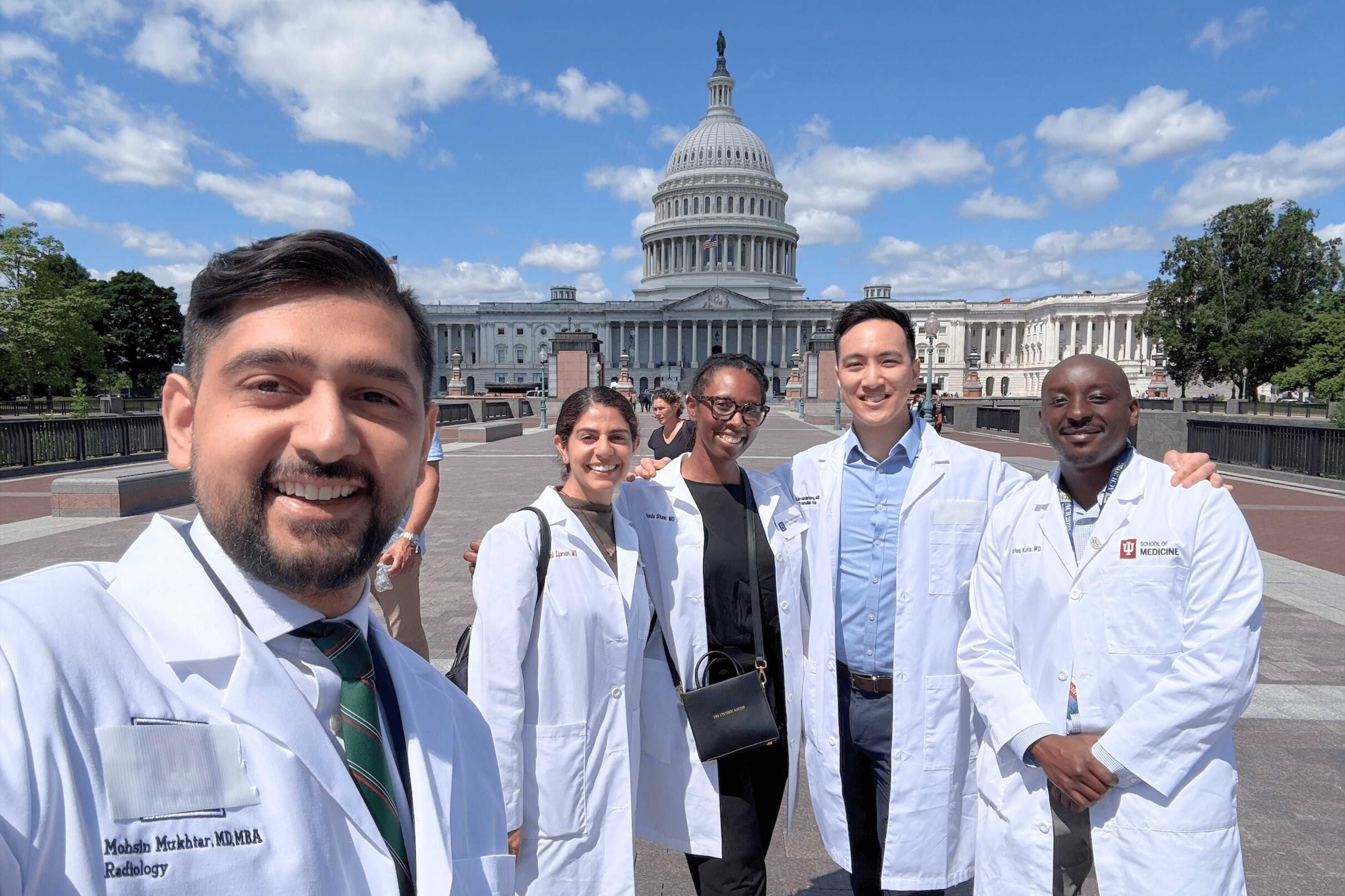 A male trainee takes a selfie with four other trainees in front of the U.S. Capitol building.