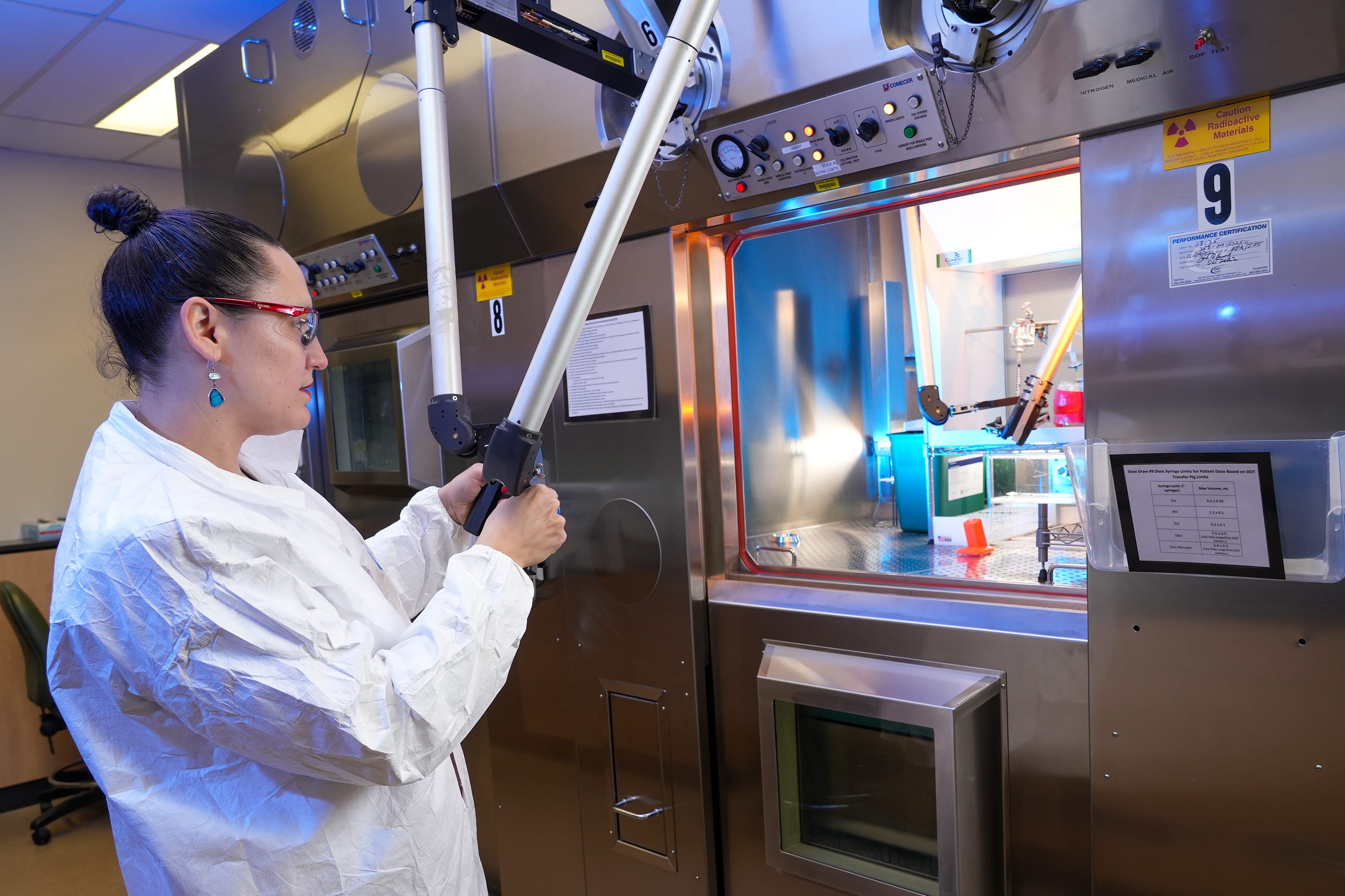 A female researcher manipulates robotic arms to move around materials.