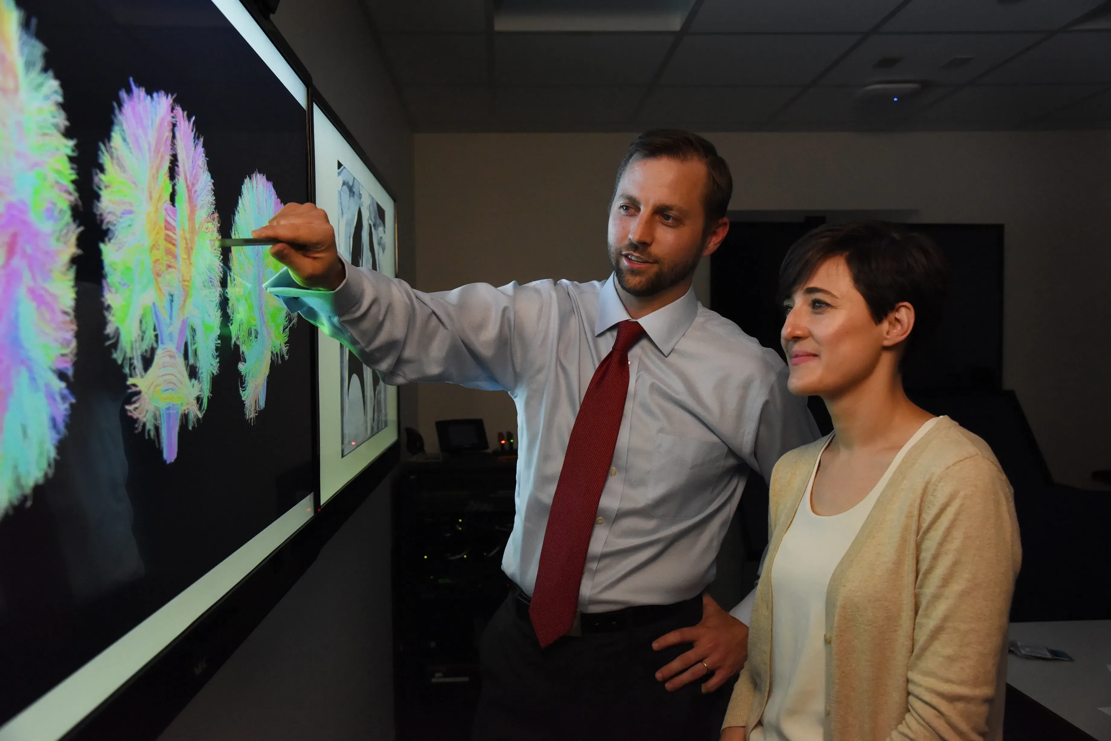 A male physician points to a neuro scan while a female physician observes,