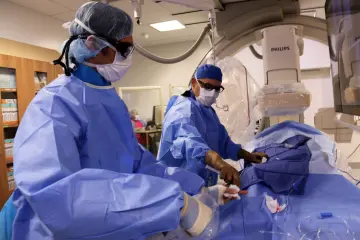 Two physicians perform an interventional procedure.