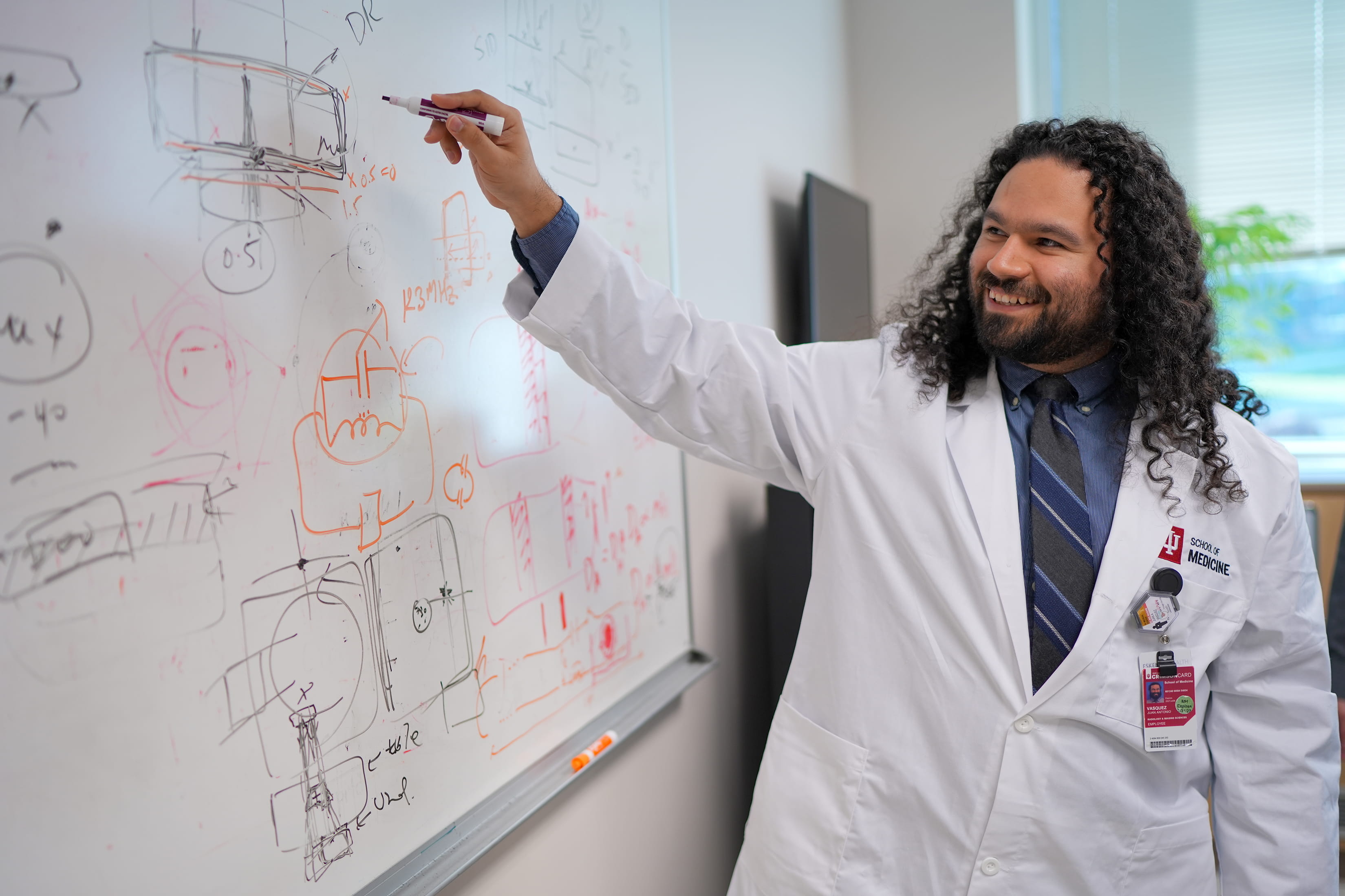 Image of male trainee smiling while writing on a whiteboard.