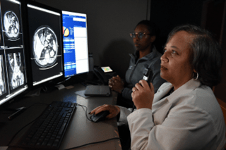 Two female radiologists annotate an abdominal scan.