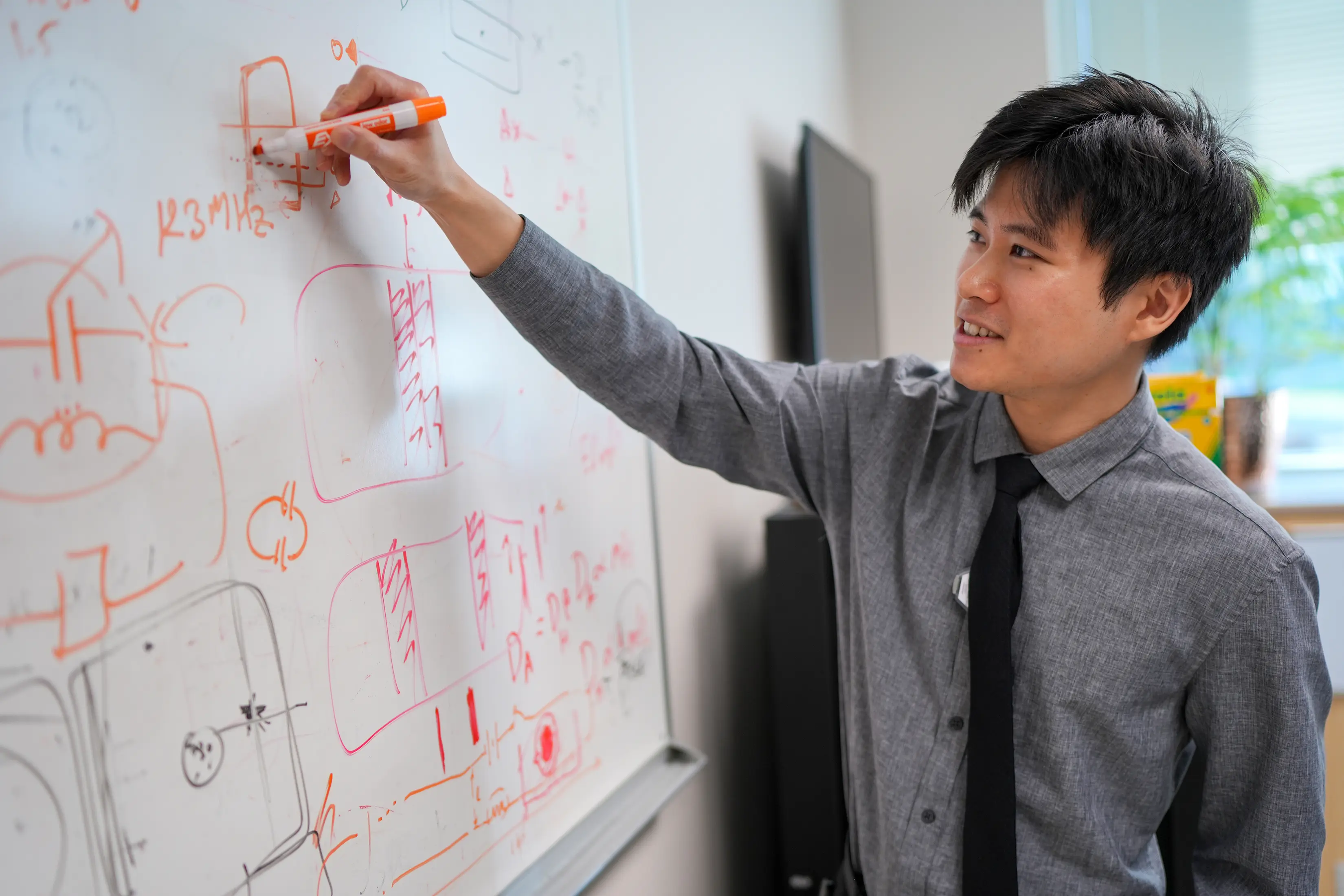 A male trainee draws on a whiteboard.