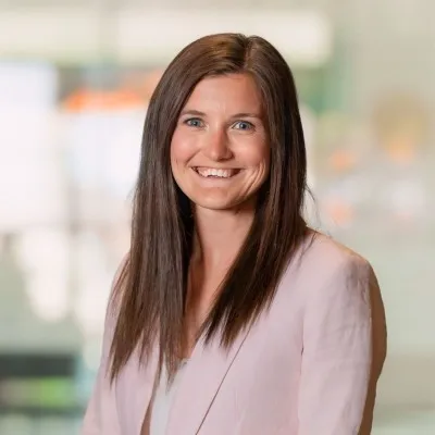 Caucasian female, Daniella Hagenseker, smiles at the camera, wearing a light pink blazer - background is blurred.