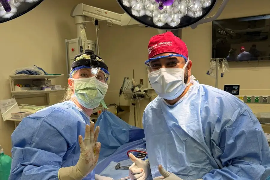 Two surgeons stand and wave at the end of a long surgery