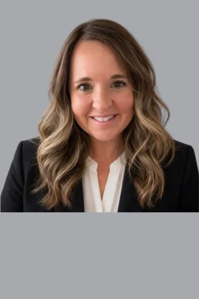 Professional headshot of Megan Rendina on a grey backdrop wearing a white top and black blazer.