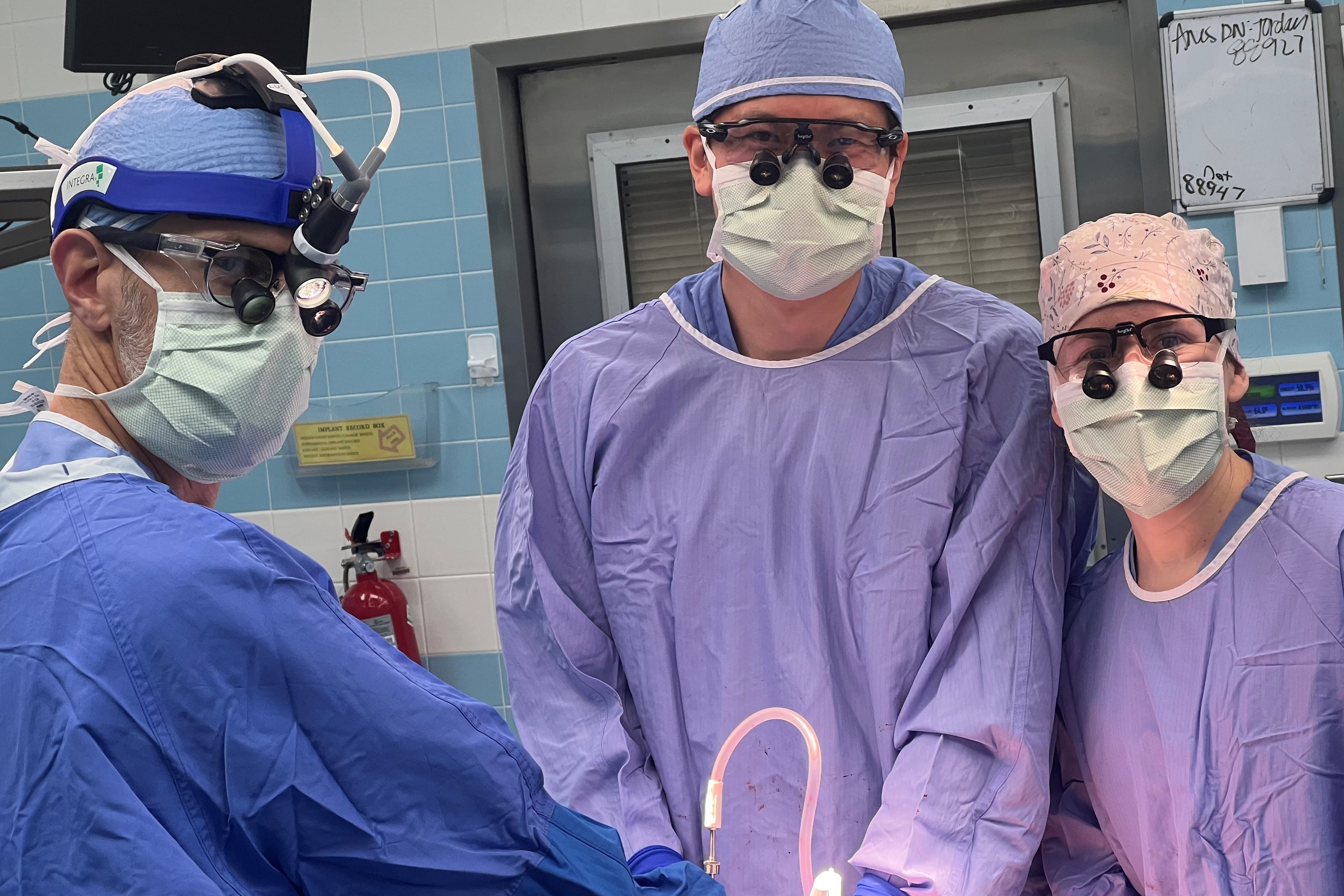 urology faculty in the operating room wearing masks, head covering, and magnifying glasses
