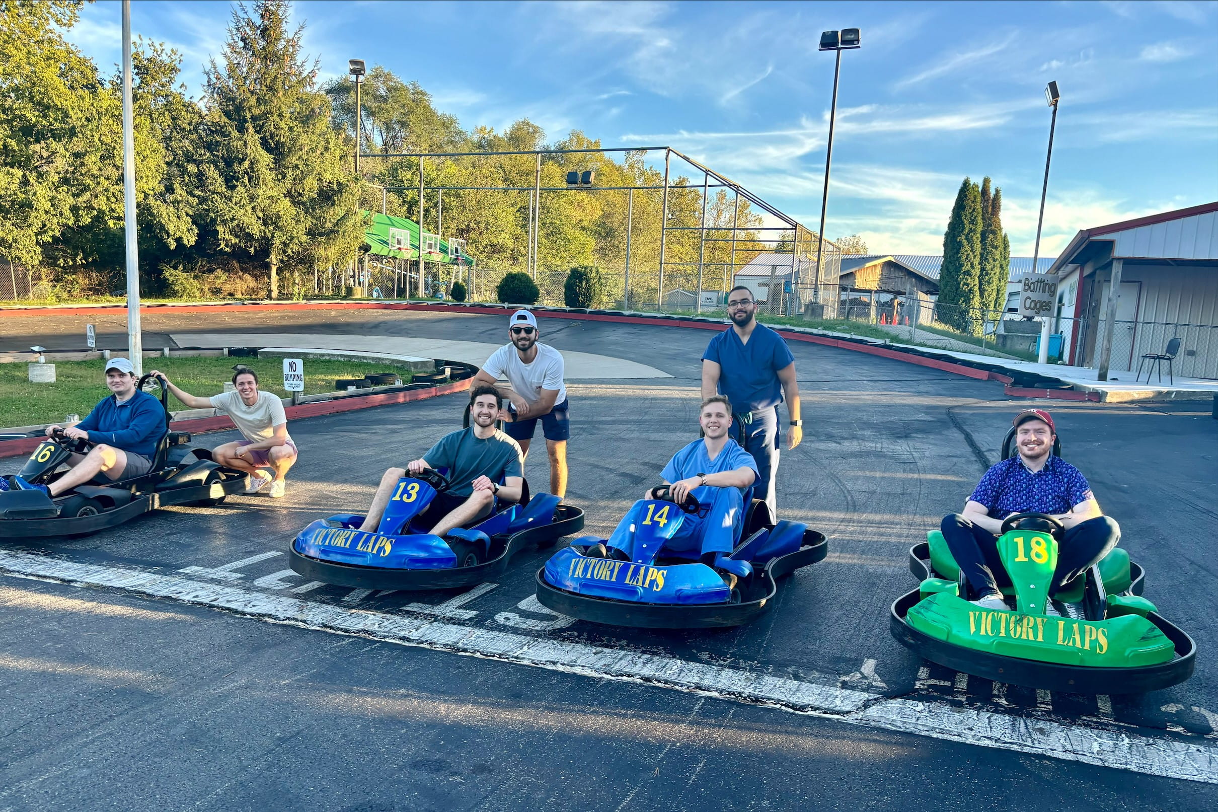 a group of residents sit in go-karts while a few others stand behind them at the starting line of a race track