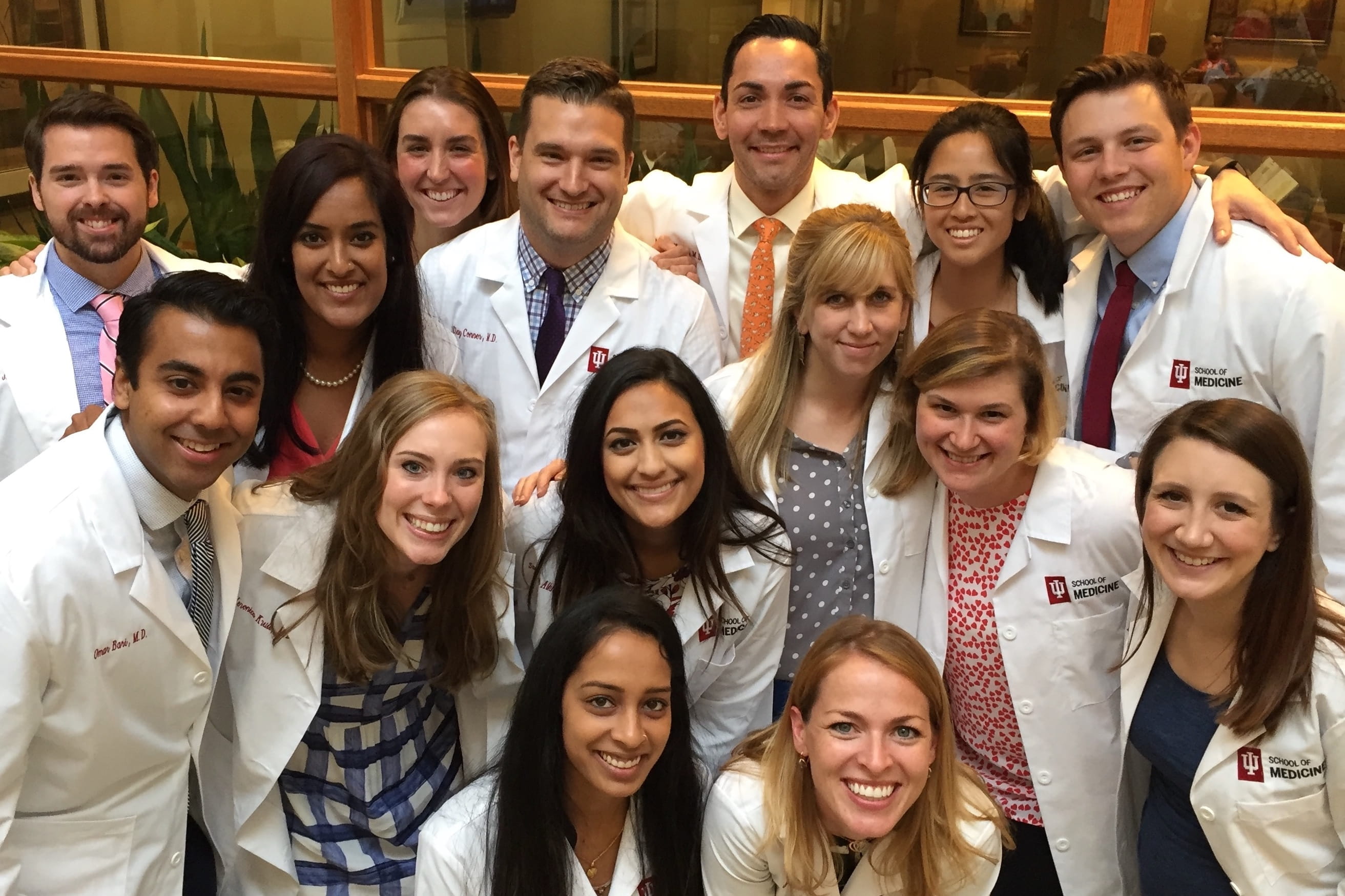 a large group of residents in white coats with their arms around each other