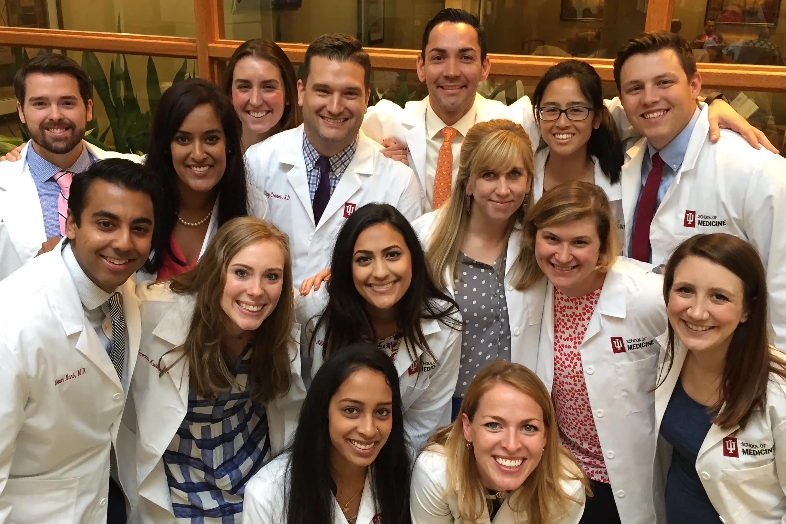 a large group of residents in white coats with their arms around each other