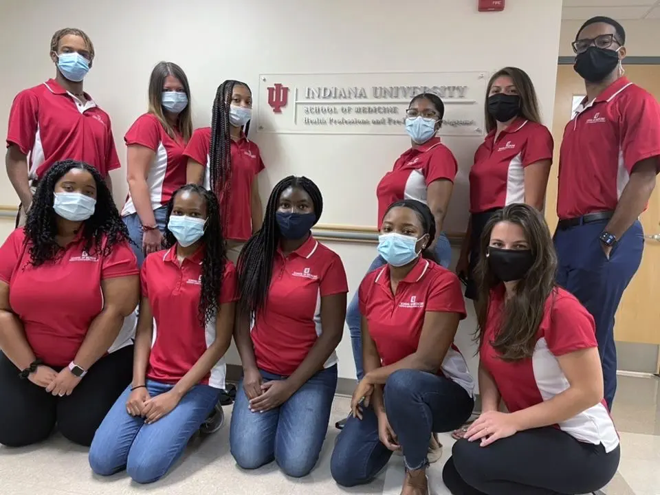 the msms cohort poses for a photo together. they are all wearing masks and red polo shirts