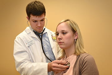 a physician listens to a patient's breathing with a stethoscope