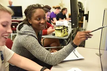 two student work together in front of a computer