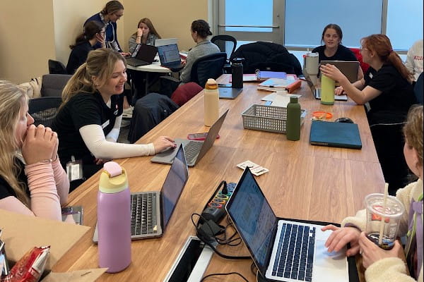 Multiple IU School of Medicine students work on laptops in class.