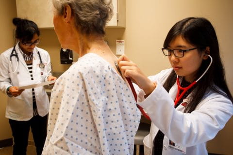 medical students learn to give a basic physical exam in the clinic with a volunteer patient