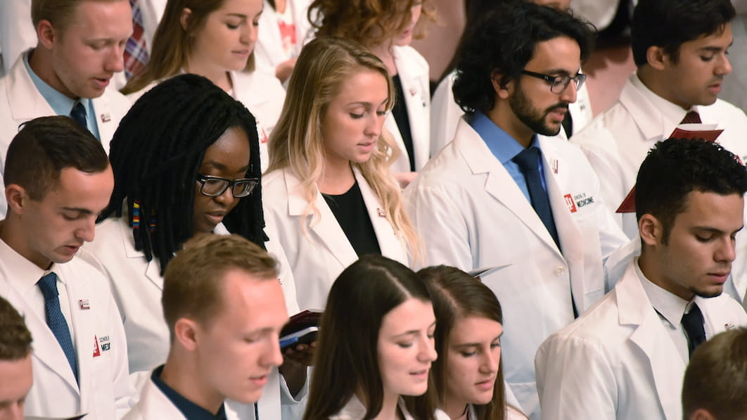 students wearing white coats take the physicians oath
