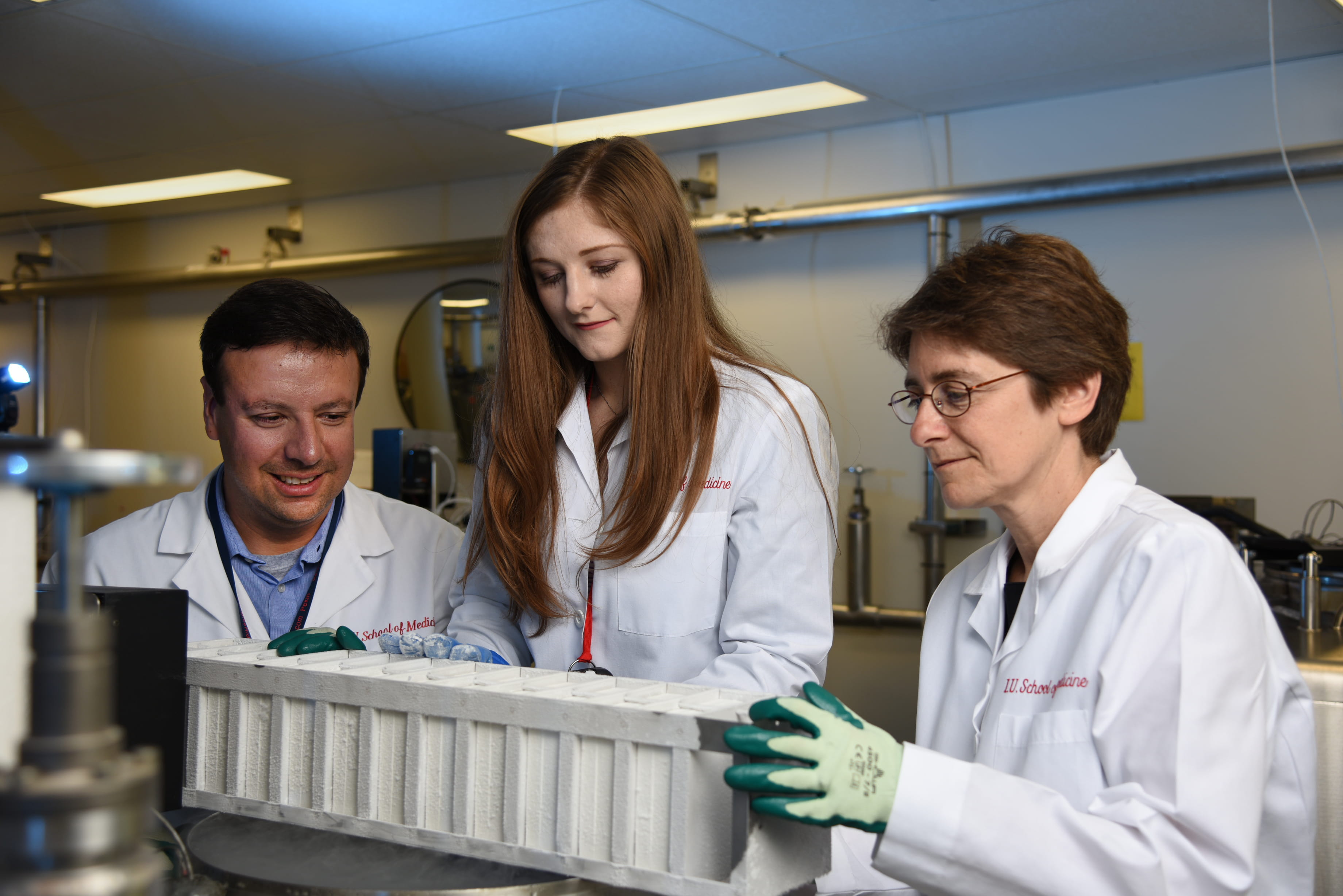 three researchers in white coats in a biobank