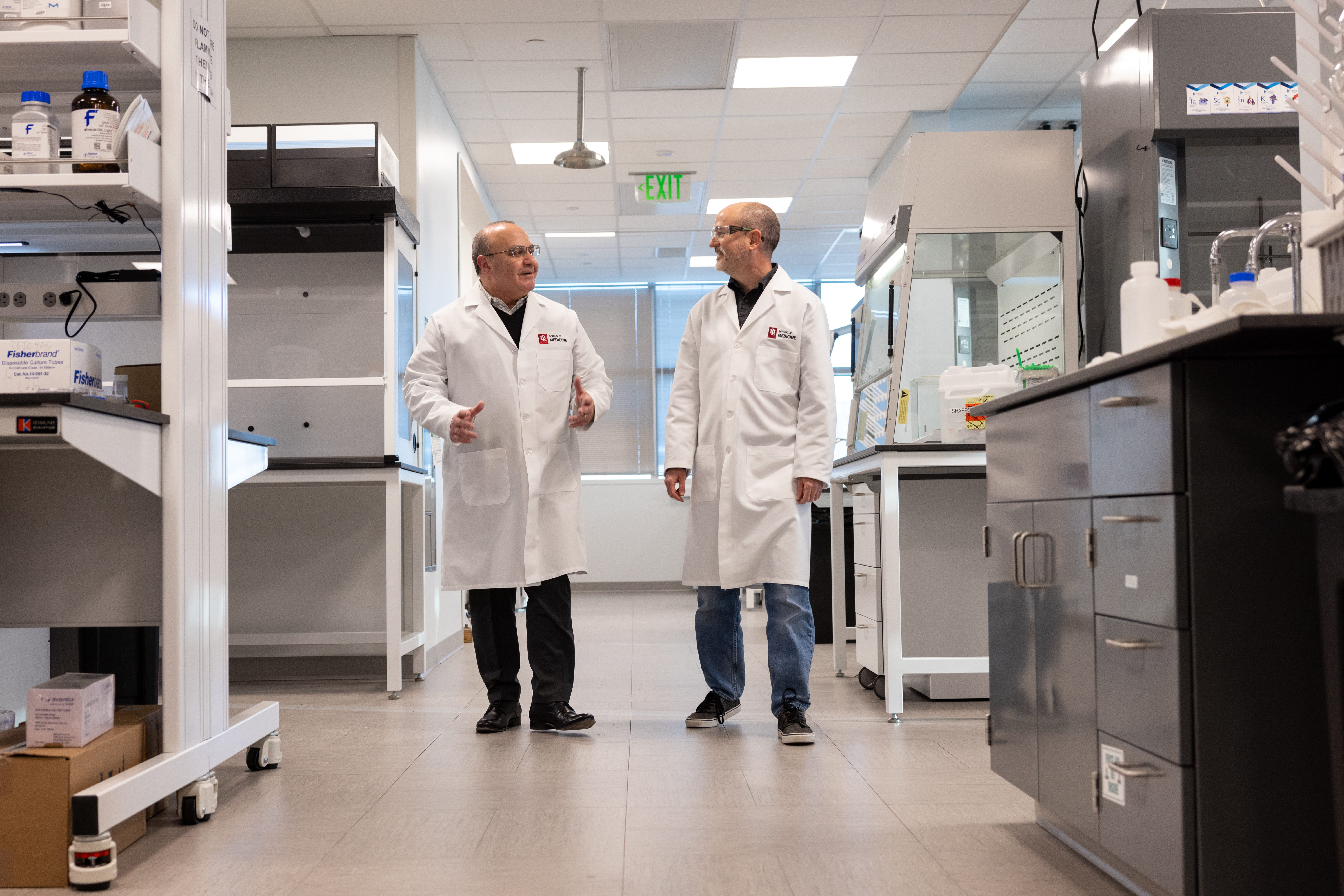 two researchers walk through a lab space