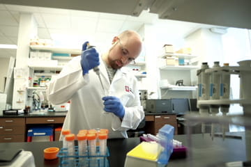 A male student pipetting liquid into a test tube.