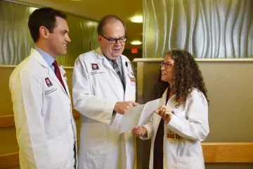 three clinicians look over a paper in the clinic