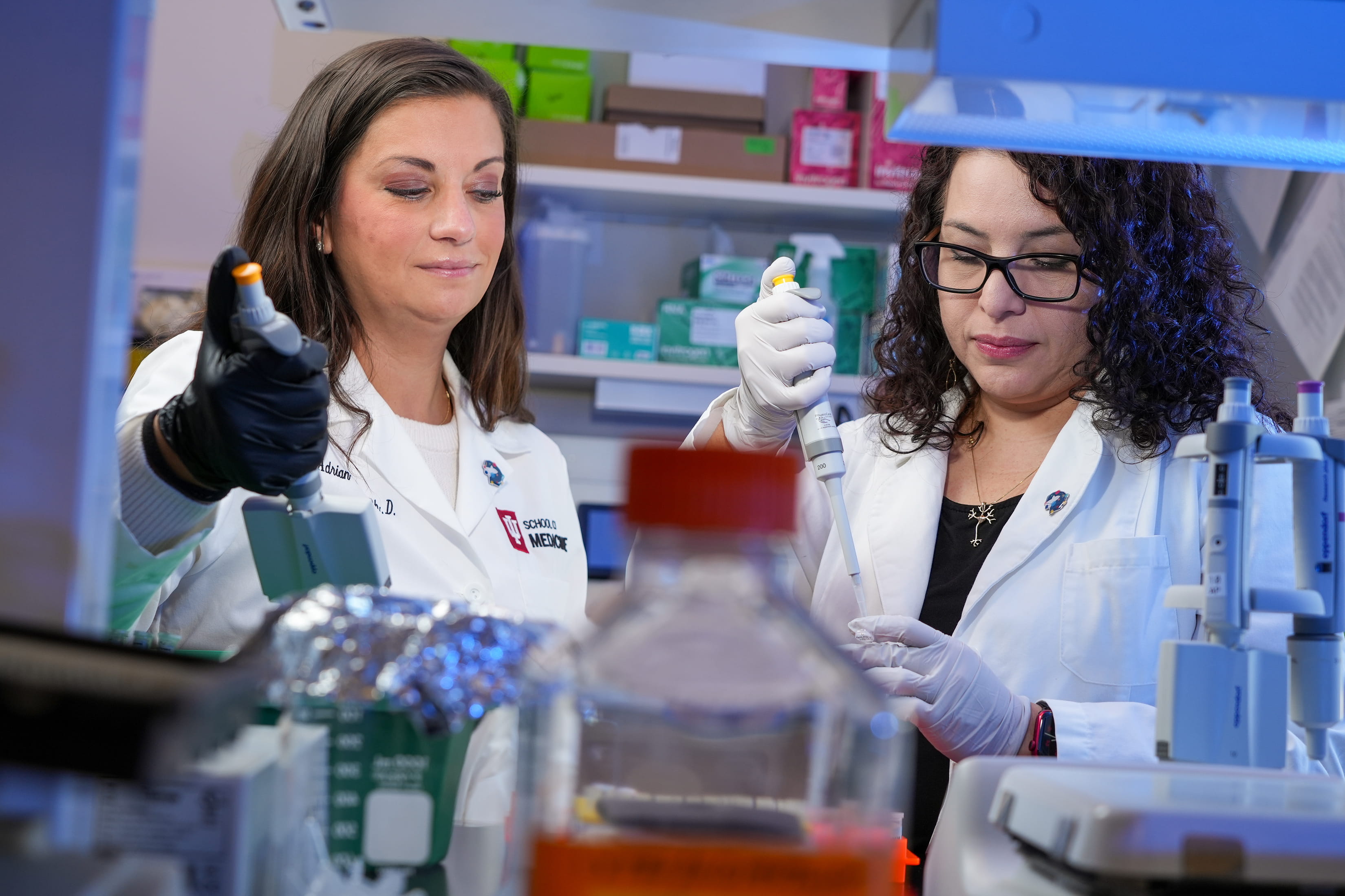 two researchers with white coats work together in the lab