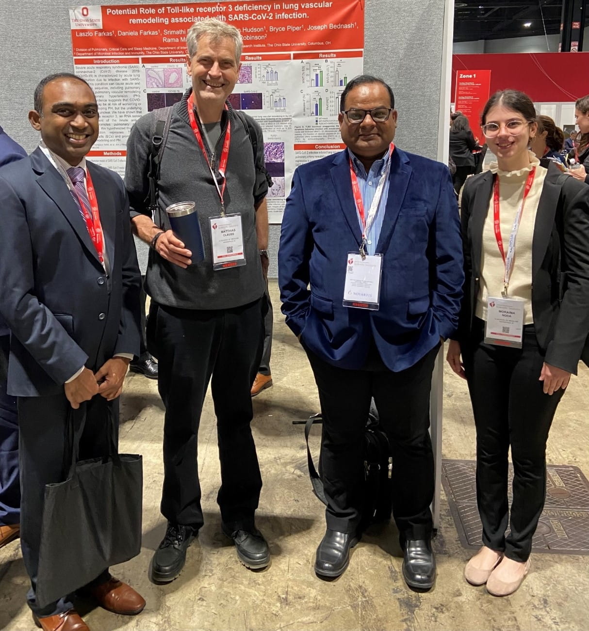 four members of the clauss lab stand together in front of a poster at research conference