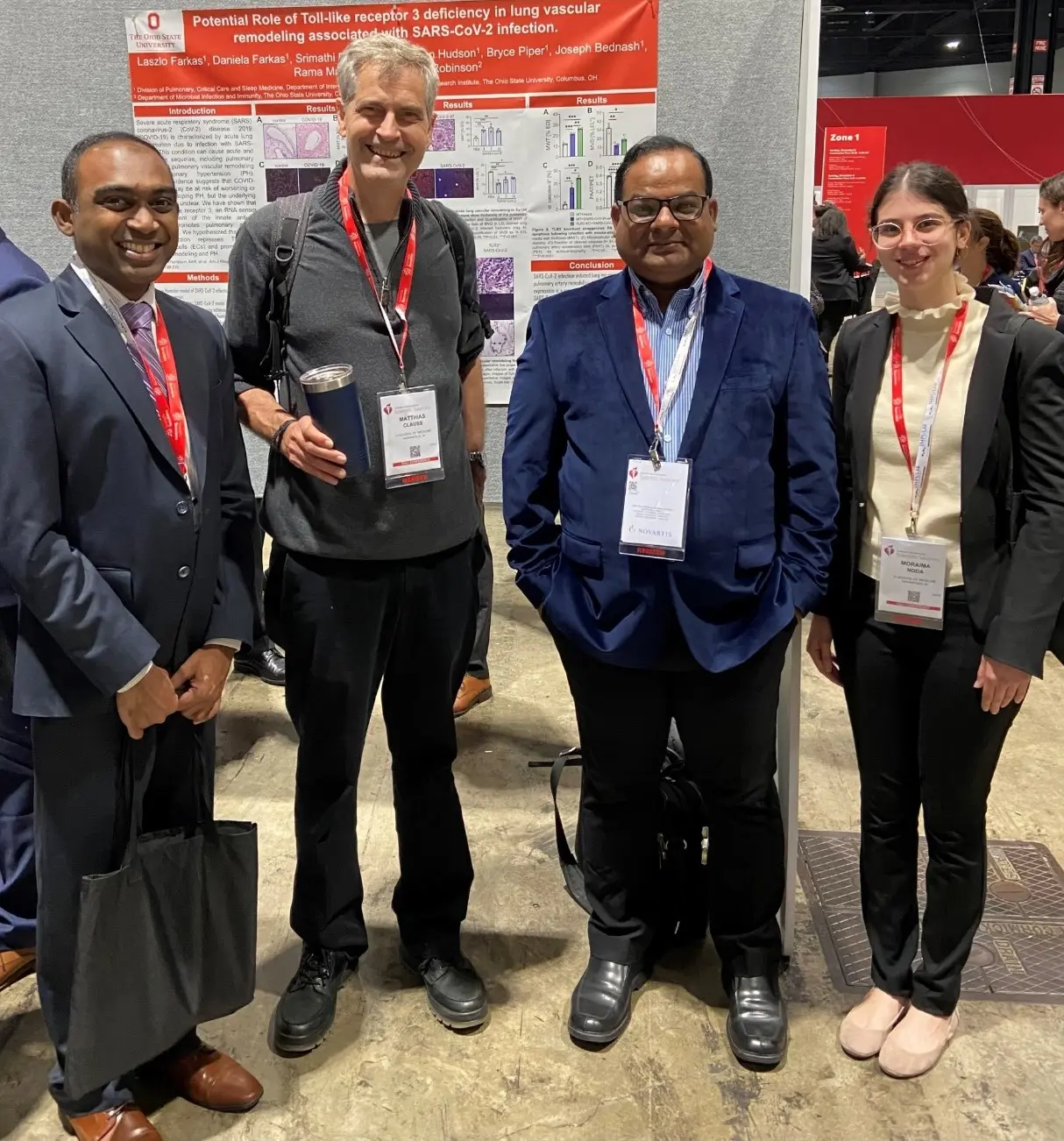 four members of the clauss lab stand together in front of a poster at research conference